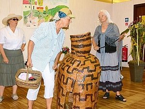 3 Schauspieler in verschiedenen Kostümen stehen mit einem großen Krug auf der Bühne.